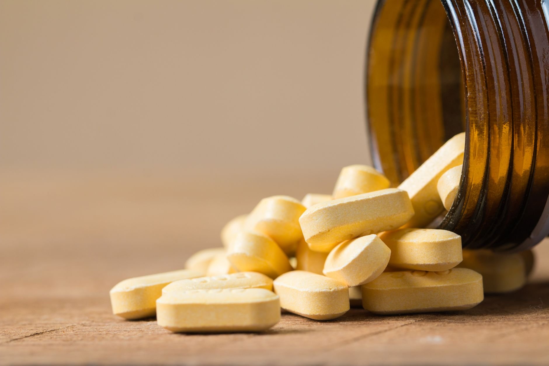 Close-up of vitamin tablets on a warm wooden surface in natural light.
