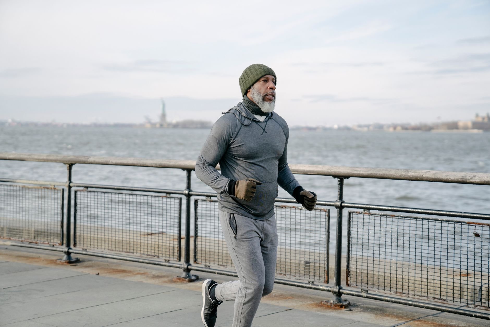 Mature man in activewear jogging by the waterfront, promoting healthy lifestyle and wellness.